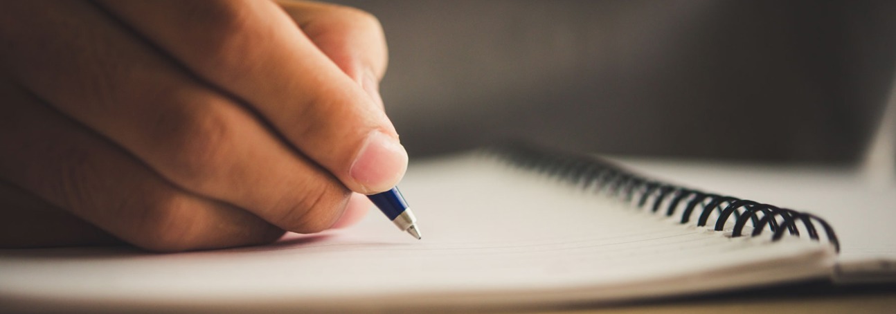 A hand holds a pen over a piece of paper