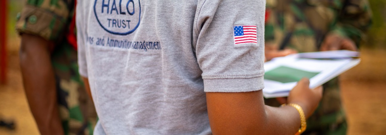 HALO staff member holds some papers and faces military personnel
