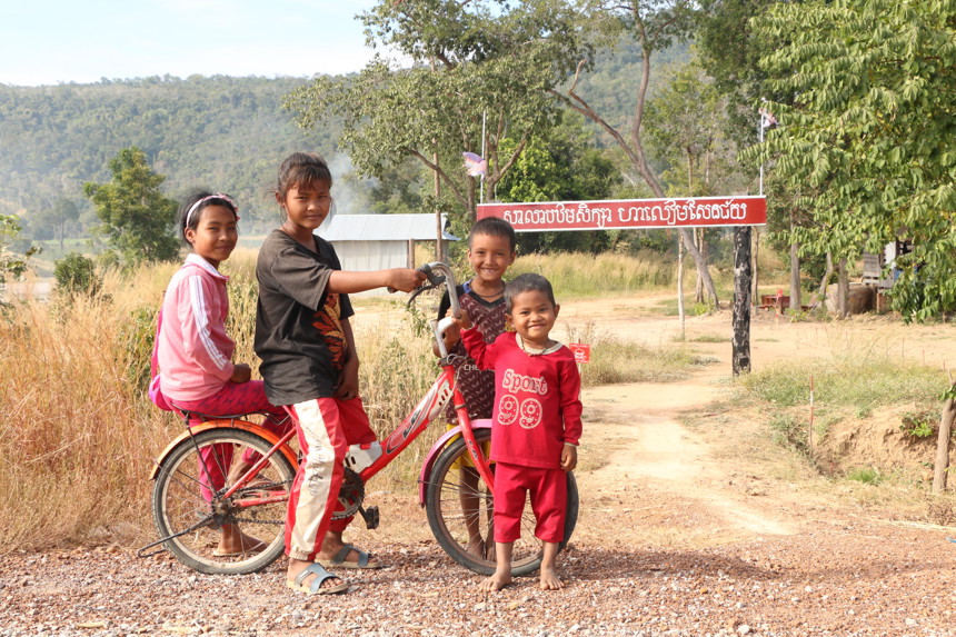 Children from Ha Leam Sen Chey Primary School pose around a bike in Cambodia