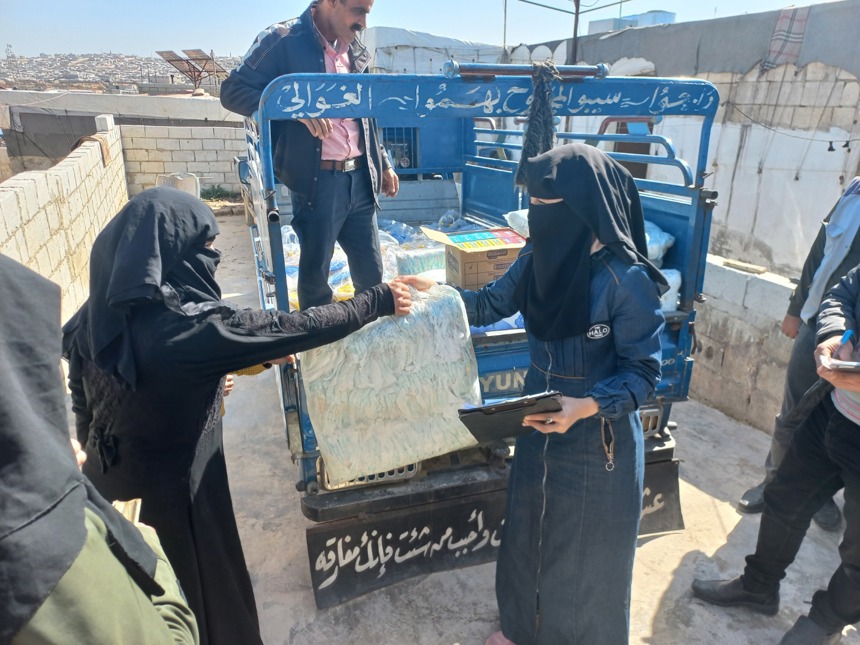 A woman hands over an item to a HALO staff member outside