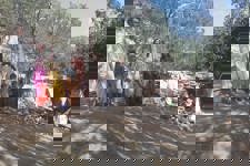 A group of children and adults stand in front of a partially built settlement