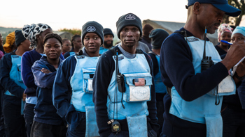 HALO deminers stand in line wearing PPE