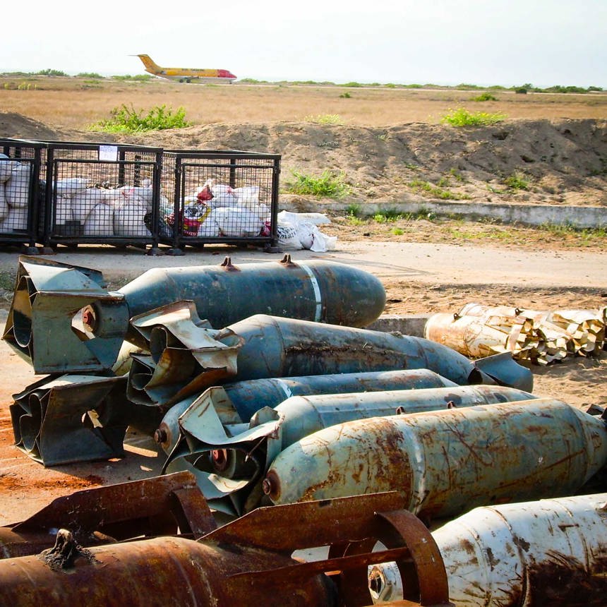 500 KG of aircraft bombs lay on the ground at Catumbela Airport as a plane is seen behind