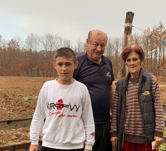 Sabit Abazi and his family stand outside an empty plot of land in Komogllavë village