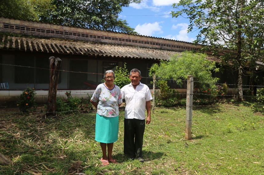Etelvina and Emiliano, from the Waikaná indigenous community stand in front of their home