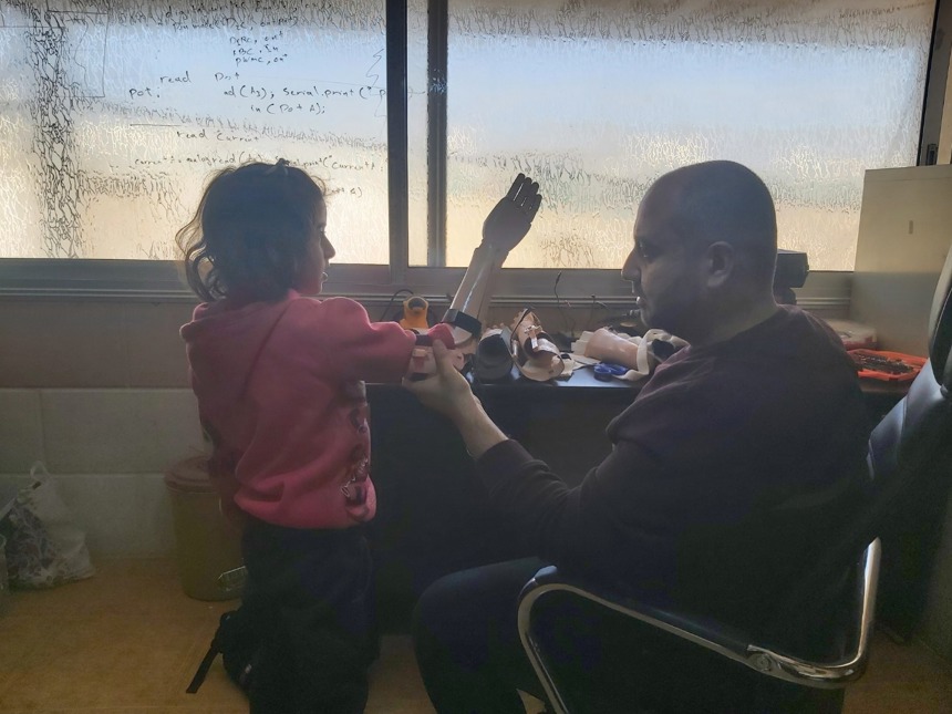 A man gives a prosthetic arm to a child in a clinic