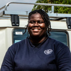 Vânia Borges, a HALO staff member smiles in front of a vehicle
