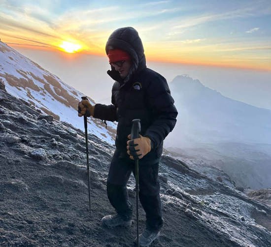 Man with trekking poles climbing Mount Kilimanjaro