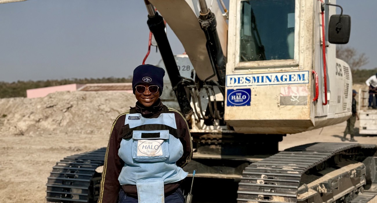 A deminer stands smiling in front of a mechanical sifter