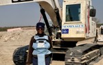 A deminer stands smiling in front of a mechanical sifter