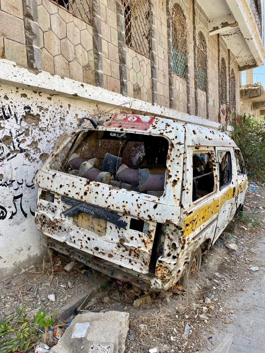 A minibus covered in bullet holes on the side of the road in Taiz, Yemen