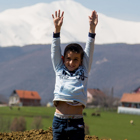 A child smiling in front of houses and a mountain