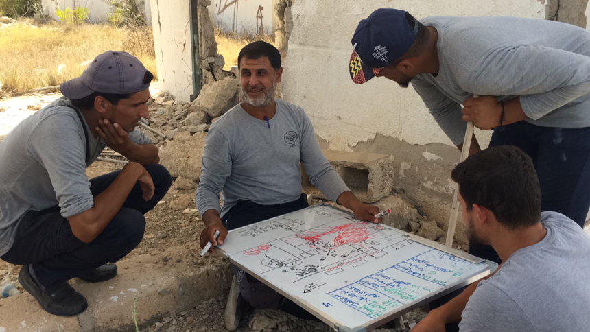 Hussain, HALO's operations manager, sits around a white board with his colleagues