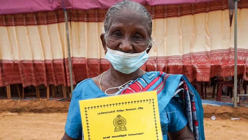 A woman stands outside holding a yellow booklet